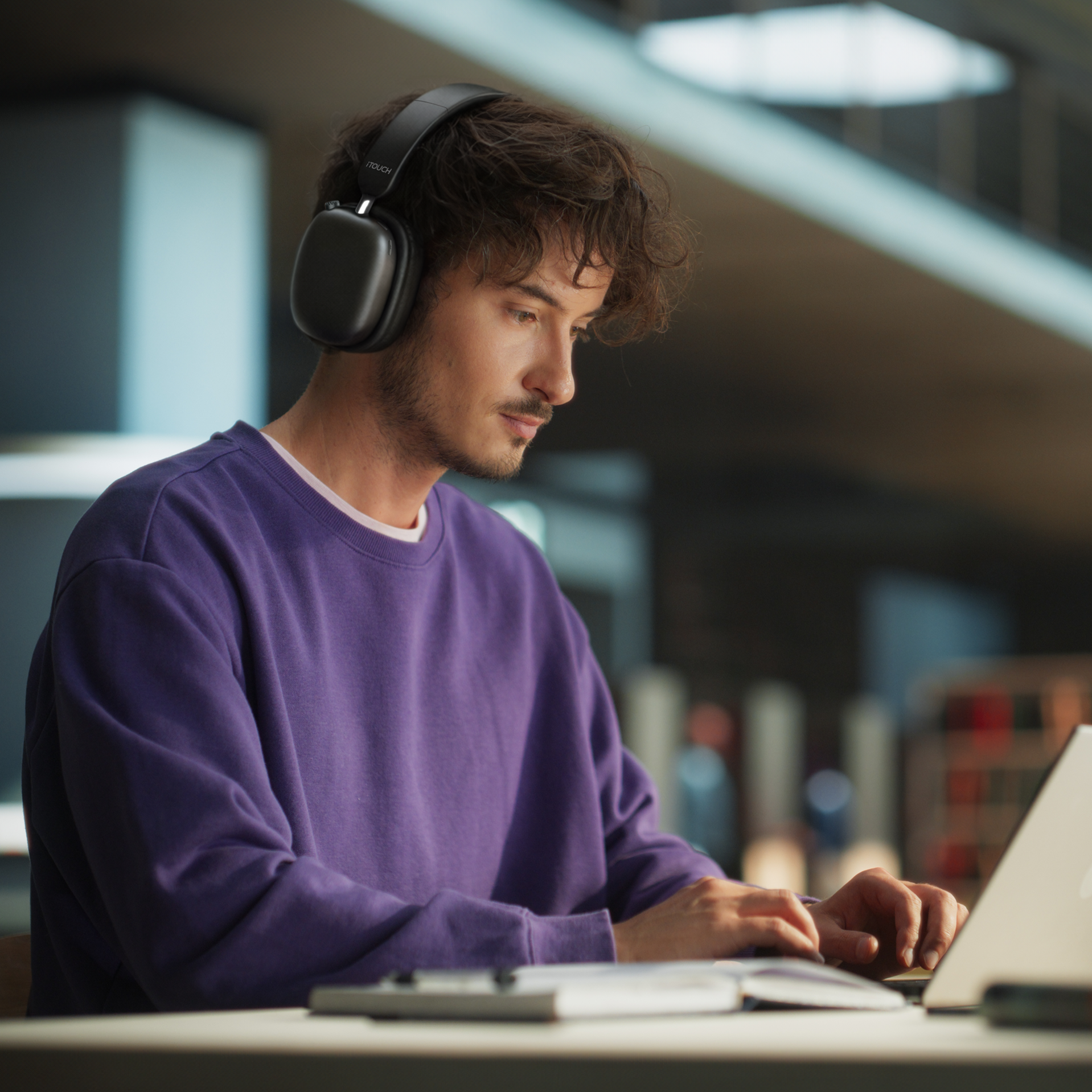 Man wearing headphones and using a laptop in a dimly lit room